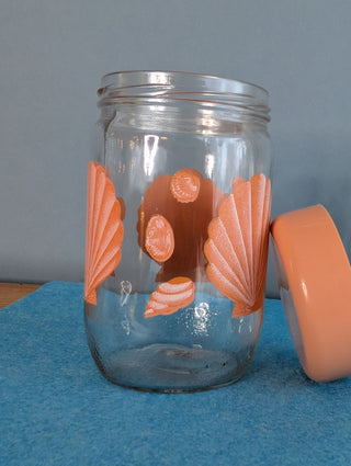 Seashells on a glass storage jar with orange plastic lid - Artful Accumulator Boutique Vintage