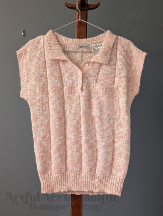 Pink knitted vest on a wooden hanger against a gray background