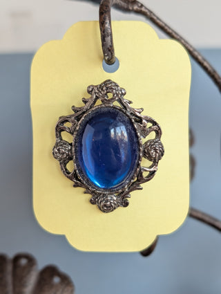 Transparent blue cabochon oval brooch with pewter-coloured floral frame