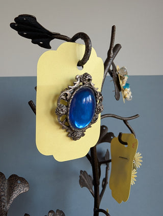 Transparent blue cabochon oval brooch with pewter-coloured floral frame